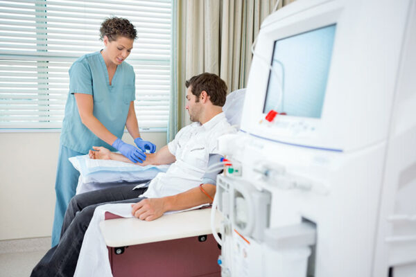 A nurse prepares an IV for a patient to be hooked up to a dialysis machine.